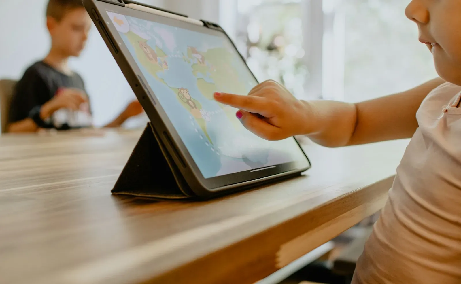 Tablet ekranında haritaya parmağıyla dokunan çocuk eli
