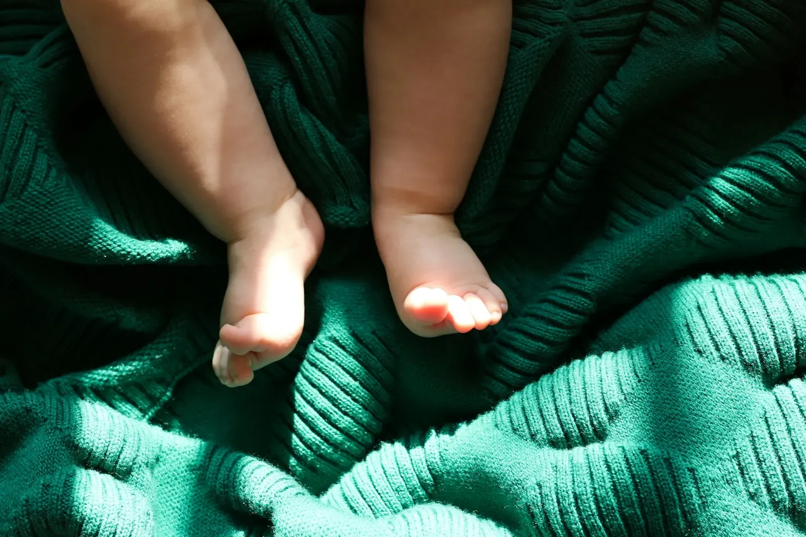 Yeşil örgü battaniye üzerinde bebek ayakları